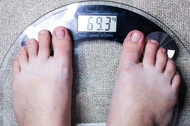 Çıplak ayaklar, şeffaf cam bir ölçekte vücut ağırlığını gösterir. Sağlık ve sağlık odaklanması.