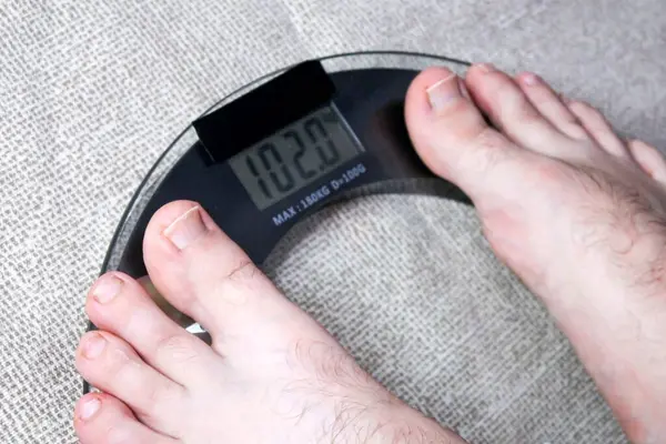 Elektronik ölçekte ayakların yakın çekimi daha yüksek ağırlık okumaları gösteriyor. Sağlık izleme kavramı.