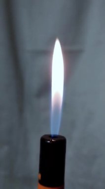 Gri bir arkaplanda yanan bir çakmak. Tam otomatik yangınlı dikey video yükle.