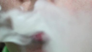 Rahat bir atmosferde, bir birey bir duman bulutu solur ve düşük ışığa karşı büyüleyici bir görsel etki yaratır. Bu an, duman dağılırken sükunetin özünü yakalar.