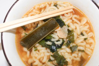 Yosun ve sebzeli erişte çorbanın içinde servis edilir. Otantik Asya usulü ramen. Tepesinde yemek çubukları var..