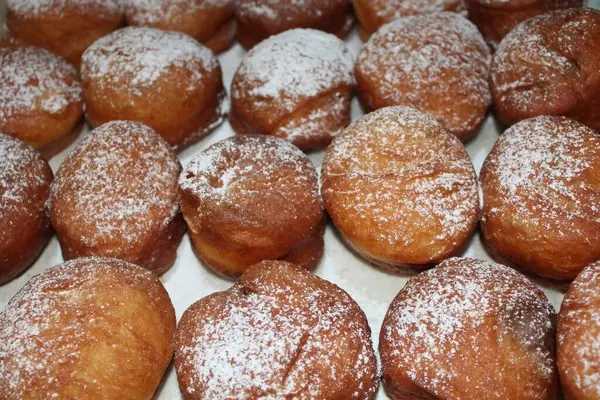 Pudra şekerli ev yapımı altın sarısı çörekler. Konforlu, ev yapımı yemek temaları ya da fırın görselleri için mükemmel..
