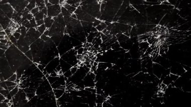 Karanlık ve parçalanmış bir cam yüzeydeki çatlakların oluşturduğu karmaşık ve hassas kalıpların ayrıntılı bir keşfi. Düşük ışık ortamında yakalanan bu görüntü, çarpıcı görsel dokuları gözler önüne seriyor.