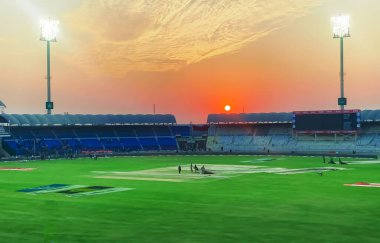 Multan Kriket Stadyumu 'nun arka planında boş sandalyeler ve yeşil çimenler var. Kriket stadyumunda renkli gün batımı.