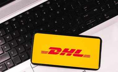 Modern transportation and delivering company DHL inside mobile screen on laptop, editorial backdrop