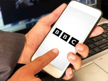 Modern BBC mobil uygulaması ekranda erkeğin dokunduğu editoryal arkaplan