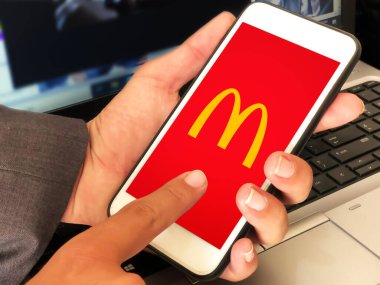 Yemek siparişi için McDonalds mobil uygulaması kullanan kişi, yazı arkaplanı