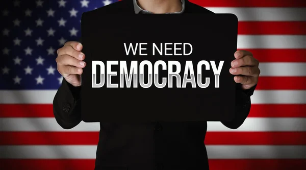 我们需要一个民主的背景 一个男人拿着海报和一面美国国旗作为背景 美利坚合众国的民主需求概念 — 图库照片
