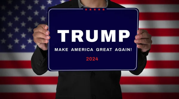 アメリカの国旗を背景に手を振っている男の手にトランプのポスター 2024年大統領選挙編集の背景 — ストック写真