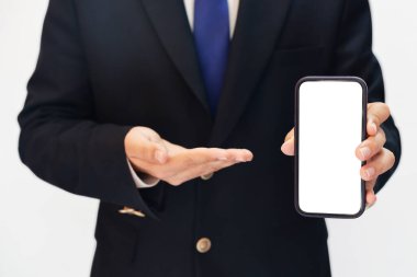 Mobil ekrana doğru bakan adam reklam için siyah fotokopi alanını gösteriyor. Mobil ekran gösteren takım elbiseli bir adam.
