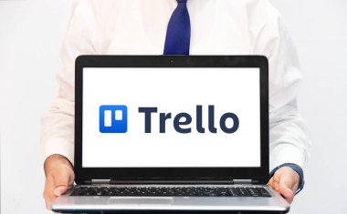 Trello web sürüm arkaplan kavramı dizüstü bilgisayar ekranı mavi kravatlı, editoryal arka planı olan biri tarafından tutuluyor