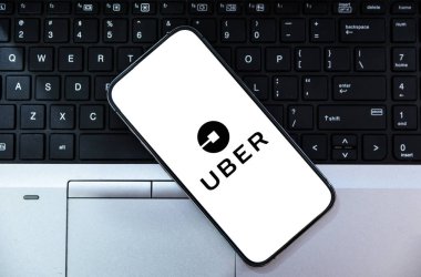 Arkaplanda dizüstü bilgisayarı olan mobil ekrandaki Uber, servis sağlayıcı şirket editör arkaplanına bin