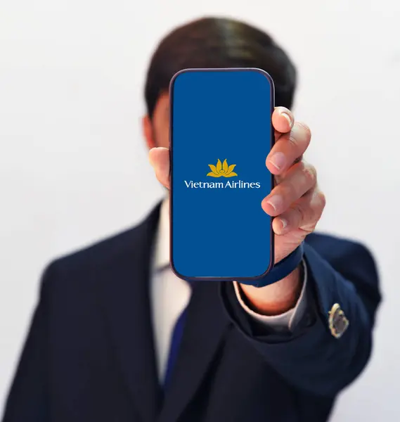 stock image Man showing Vietnam airlines on smartphone for online booking of flights, editorial background