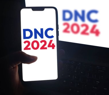 Mobil ekranda DNC 2024 haberleri, başkanlık seçim arkaplanı.