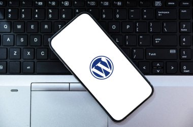 WordPress App on Mobile Screen with Laptop Background for Seamless Website Management and Blogging from Any Device