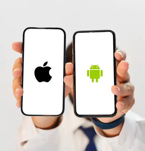 stock image Apple Vs Android Editorial Background Featuring Two Smartphones in Hand for a Visual Technology and OS Comparison