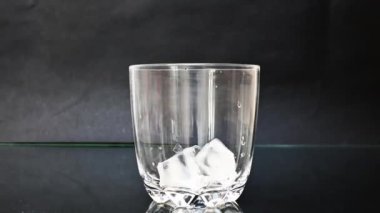  Buz küpleri ve kola içecekleri, siyah arkaplanlı 4K 'lık cam bir arkaplana dökülüyor.