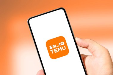Temu Etrade platform mobil uygulamasını el ve bulanık fon ile kapatın. Çevrimiçi alışveriş uygulaması Temu 'nun cep telefonu, illüstrasyonal yayın geçmişi