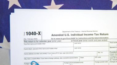 Düzeltilmiş A.B.D. Arka planda Amerikan bayrağı olan bireysel vergi iadesi formu, 4K görüntü. Kopyalama alanı olan 1040 x kağıt formu