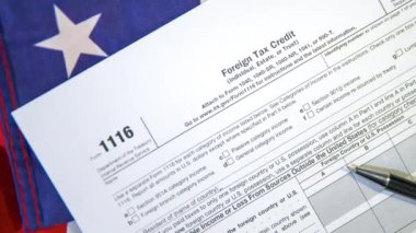 Bireyler için yabancı vergi kredi formu ve diğerleri ABD bayrağına yerleştirildi, 1116 formunun 4k görüntüsü.