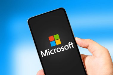 Mobil Telefon Ekranındaki Microsoft Şirketi mavi bulanık arkaplanlı, illüstrasyonlu yazı işleri. İşletim sistemi mikrosoft arkaplanı