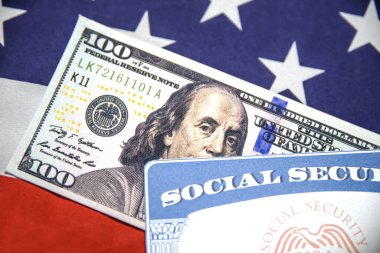 Sosyal Güvenlik Kartı ve 100 dolarlık banknot arka planda Amerikan bayrağı ile yakın plan çekimleri. ABD sosyal güvenlik kavramı