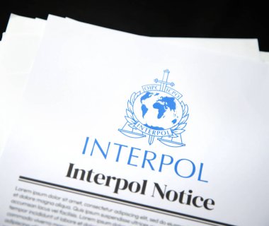 7.1.2025, Birleşik Devletler. Siyah izole edilmiş yüzey arkaplanına yerleştirilmiş kağıt formunda Interpol bildirimi. Resimli yazı arkaplanı