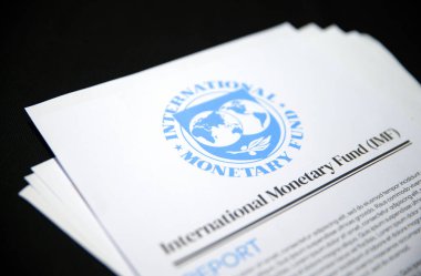 1.7.2025, Birleşik Devletler. Uluslararası Para Fonu raporları, IMF 'nin logo ve illüstrasyon raporlarına odaklanmış siyah bir arkaplana yerleştirildi