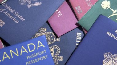 Farklı milletlerden birden fazla pasaport koleksiyonu 4K görüntü kalitesinde. Kanada, ABD, İngiltere ve diğer ülkelerin seyahat belgeleri