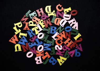 Siyah kumaş arka planında rastgele ve renkli alfabeler.