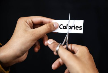 Kaloriler bir makas ile kavramı elle keser, siyah arkaplan ile kapatır.