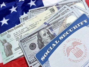 Sosyal güvenlik kartı, hazine çeki ve arka plandaki Amerikan bayrağındaki döviz faturaları. Amerikan vatandaşı, yardımlar, fonlar.