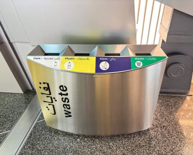 Hem İngilizce hem de Arapça etiketli farklı atık türleri için kompartımanları olan modern, metalik bir geri dönüşüm kutusu.
