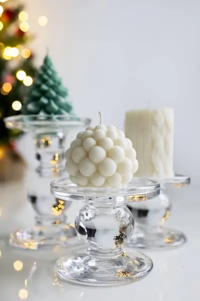 Soy candles on clear glass candlesticks. Christmas table decor. Bubble candles. Photo