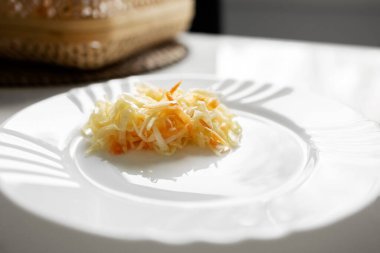 Beyaz tabakta lahana ve havuçlu salata, masa. Fotoğraf.