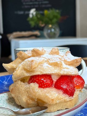 Kafeteryada taze çilekli profiterol tabağı. Fotoğraf.