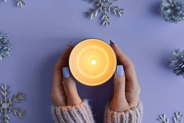 Stock image Female's hands with purple manicure holding a burning soy candle. Winter season concept, top view