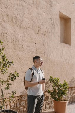 Genç Arap erkek yetişkin dışarıda duruyor ve elinde bir fincan kahve tutuyor. Eski kasabadaki Lübnanlı bir adamın portresi. Z jenerasyonu kavramı 