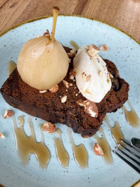 Karamelli armut, krema, doğranmış fındık ve karamel şurubuyla servis edilen çikolatalı pasta. Tatlı yemek.