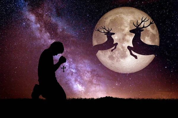 Man praying with night deer silhouette against the backdrop of a large moon element of the picture is decorated by NASA