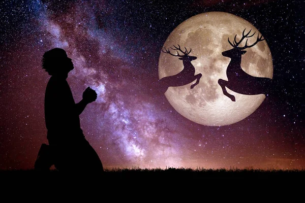 Man praying with night deer silhouette against the backdrop of a large moon element of the picture is decorated by NASA