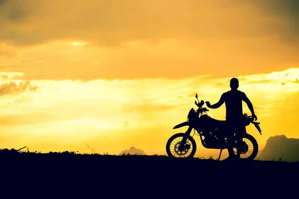 Man with Motocross bike with mountain view in beautiful sunset lights. motorcycle travel concept
