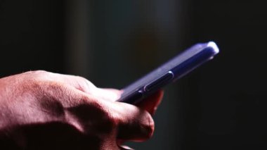 Cep telefonu kullanan bir adam. Adamın elleri cep telefonundan bilgi arıyor