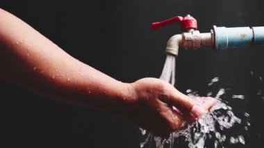 The concept of having clean water to use. Man washing hands. Clean water flowing from faucet on black background
