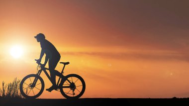 Akşamları çayırda egzersiz yapan bisikletçi silueti, sağlık hizmeti konsepti
