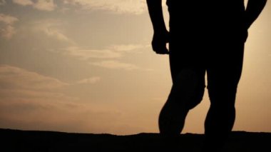 Gün batımında dağlarda antrenman yapan bir adamın silueti. 