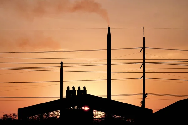 silhouette of industrial factory building in the city with electric cables