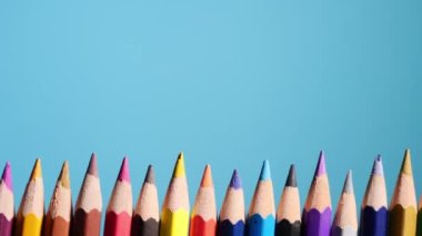 Yakın çekim video, mavi arka planda renkli ahşap kalemlerin hareket eden kamerası. Bireysel farklılıklar kavramı.