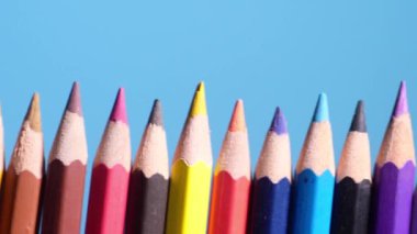 Yakın çekim video, mavi arka planda renkli ahşap kalemlerin hareket eden kamerası. Bireysel farklılıklar kavramı.