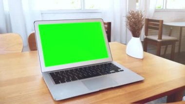 Tatilde bir kahve dükkanındaki ahşap bir masaya yerleştirilmiş yeşil ekran laptop..